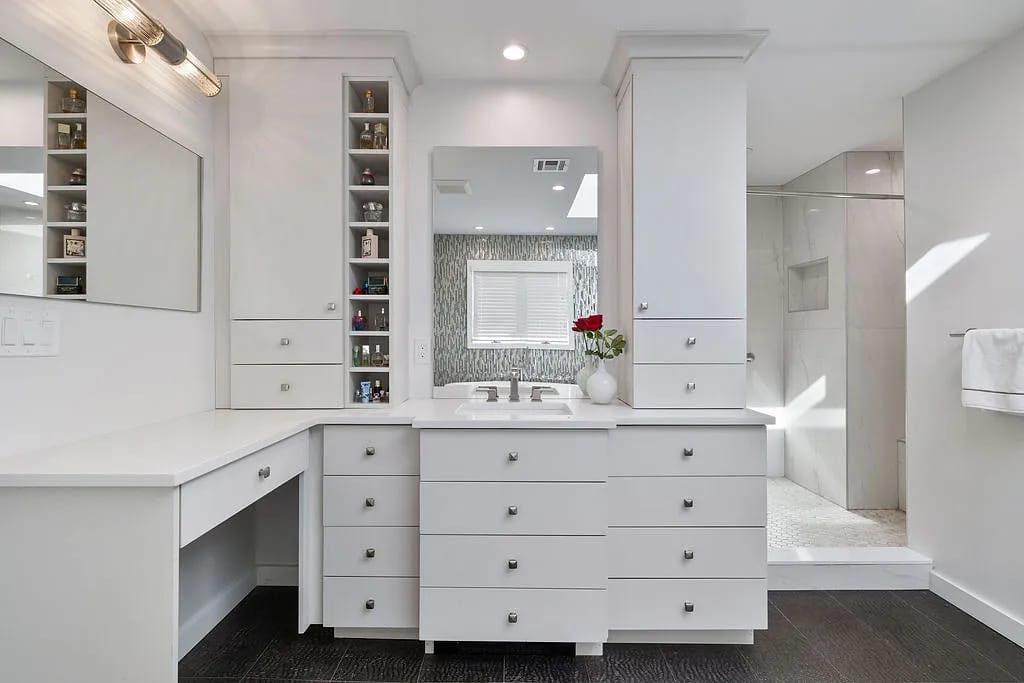 Bathroom with white double vanity, separate shower, dark flooring, and flowers on the countertop