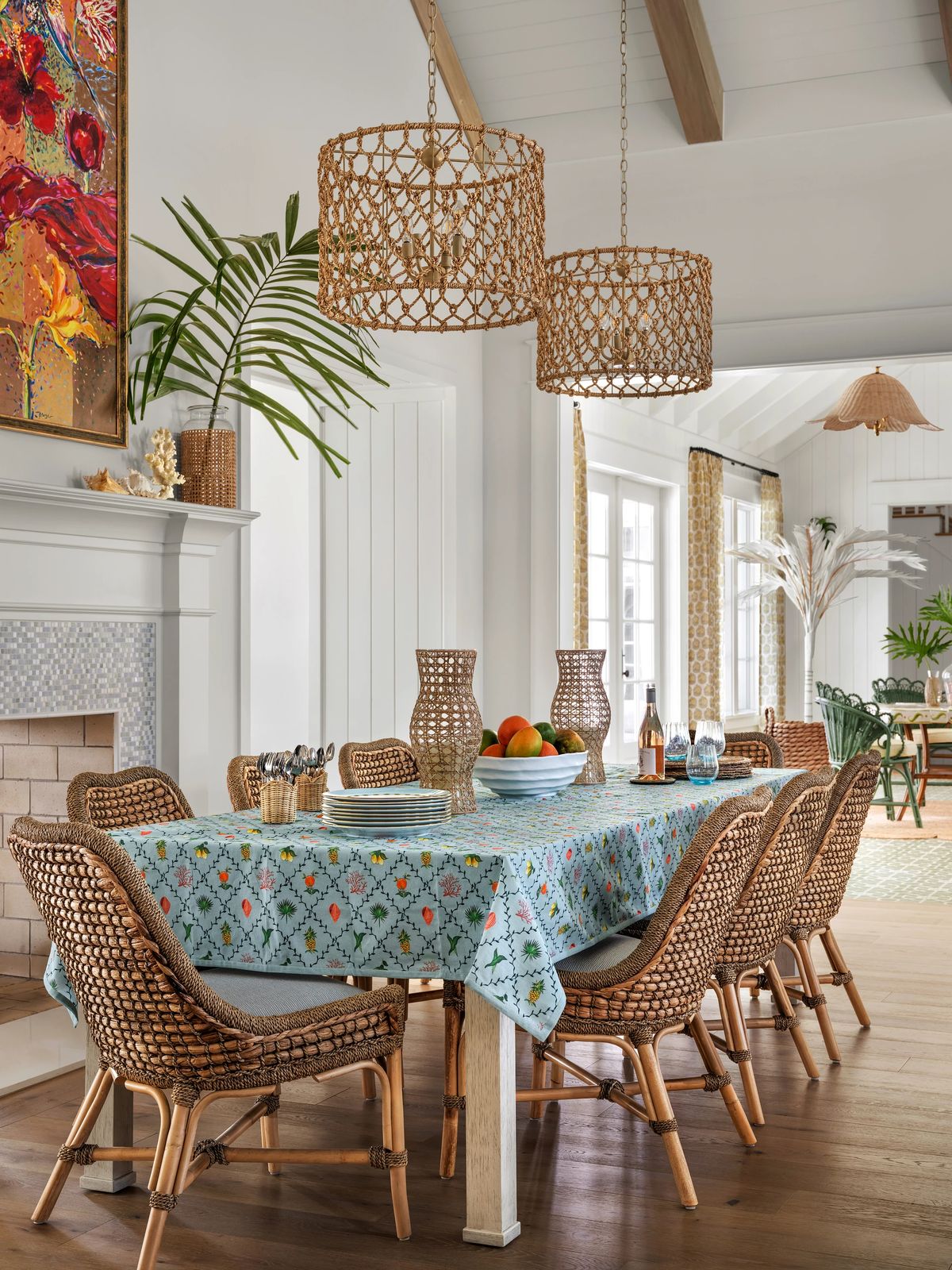 Dining room with rectangular table, wicker chairs, patterned tablecloth, and hanging pendant lights.