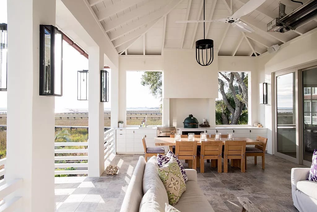 Outdoor deck with dining table, sectional sofa, grill, stone flooring, and lanterns under a wooden ceiling.