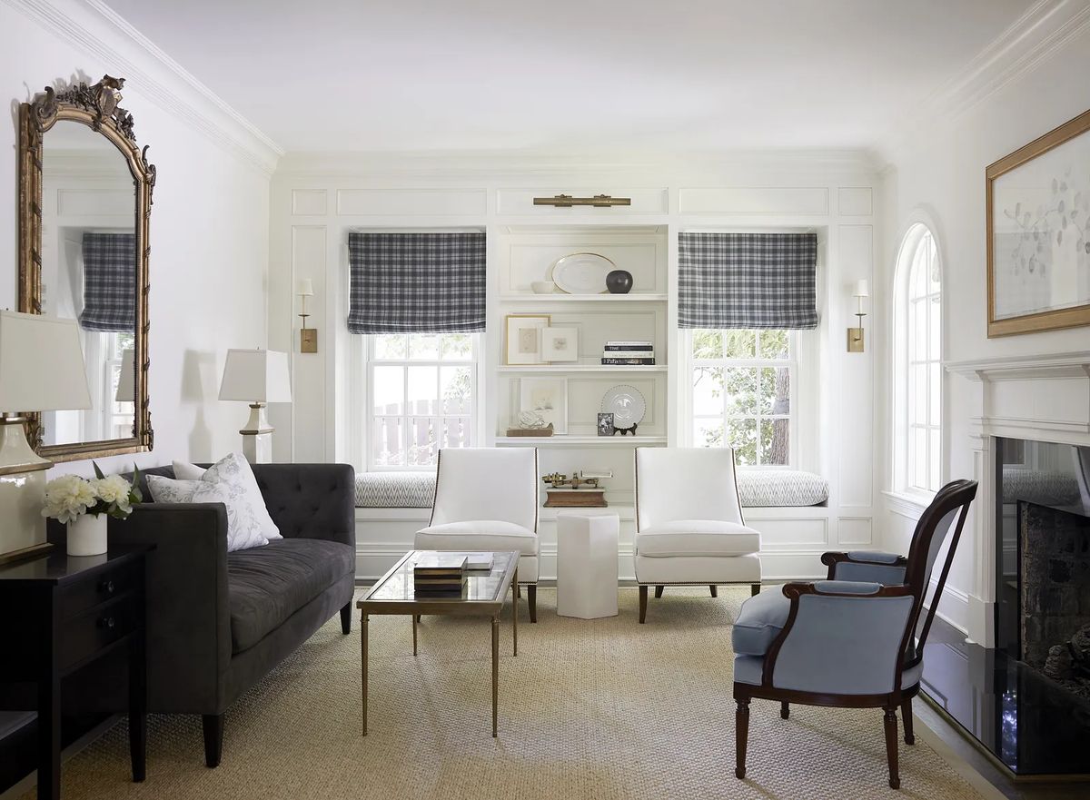 Living room with gray sofa, white chairs, glass coffee table, built-in bookshelf, and fireplace