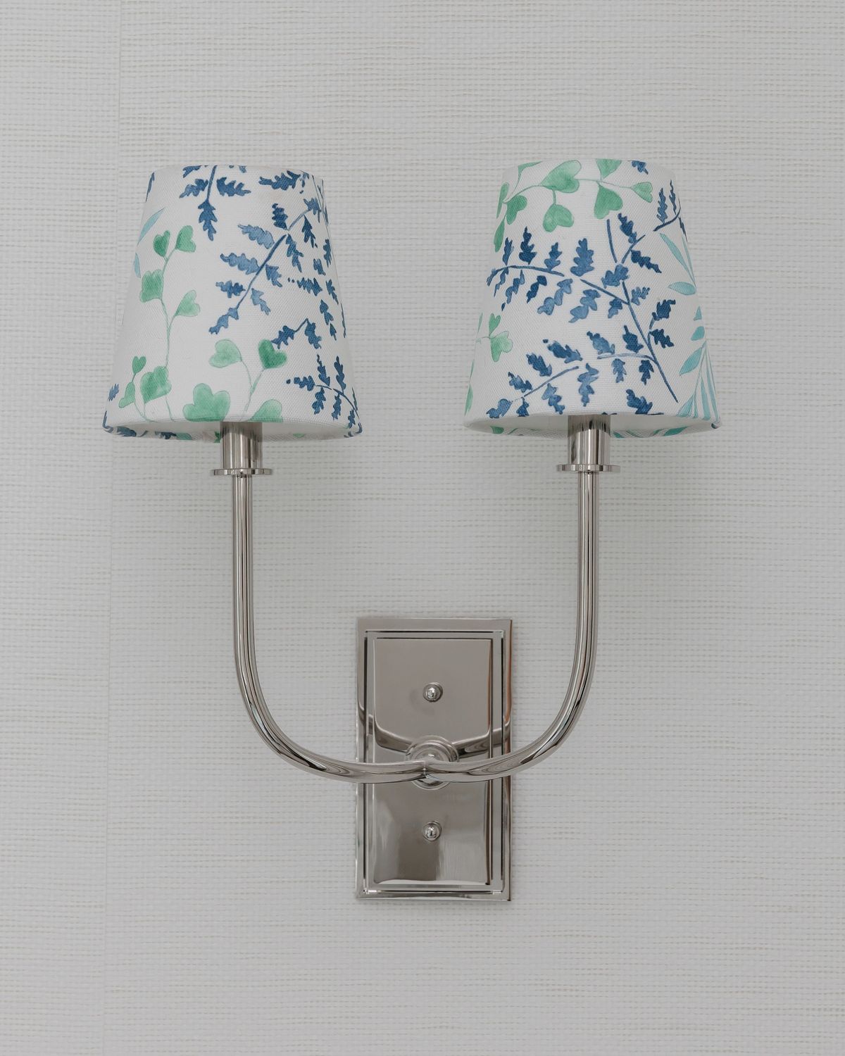 Wall-mounted sconce with floral fabric shades on a silver base.