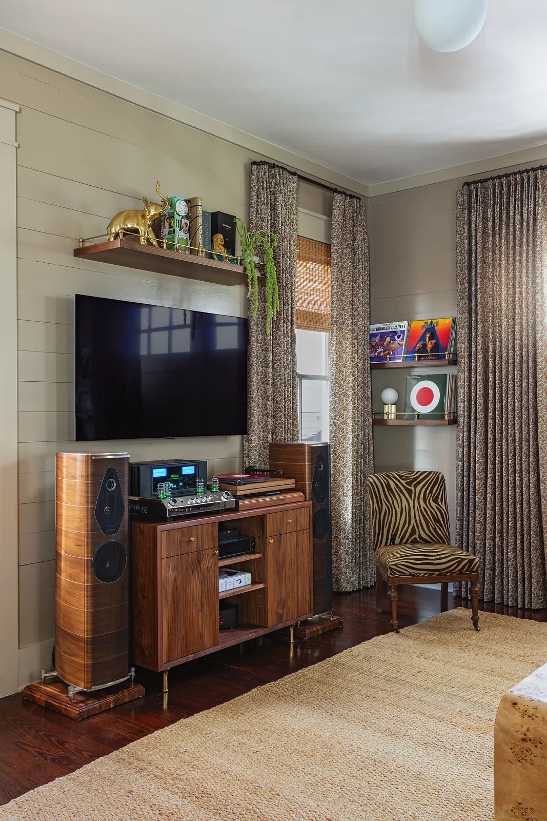 Living room with media console, speakers, flat-screen TV, decorative chair, and area rug.