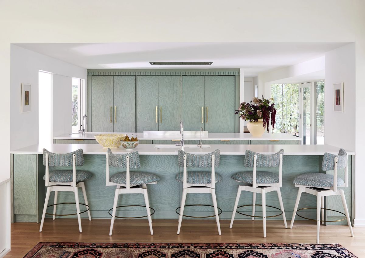 Kitchen with central island, white countertop, light green cabinetry, and tall stools.