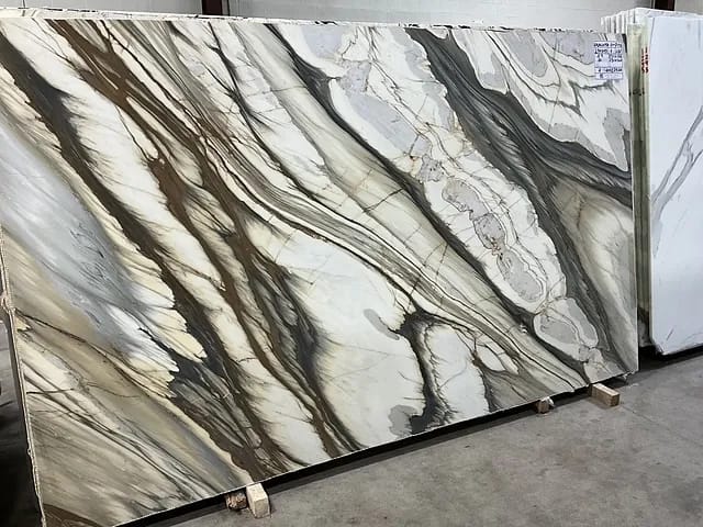 Display of large stone slabs with intricate patterns in beige, gray, and brown in an industrial setting.