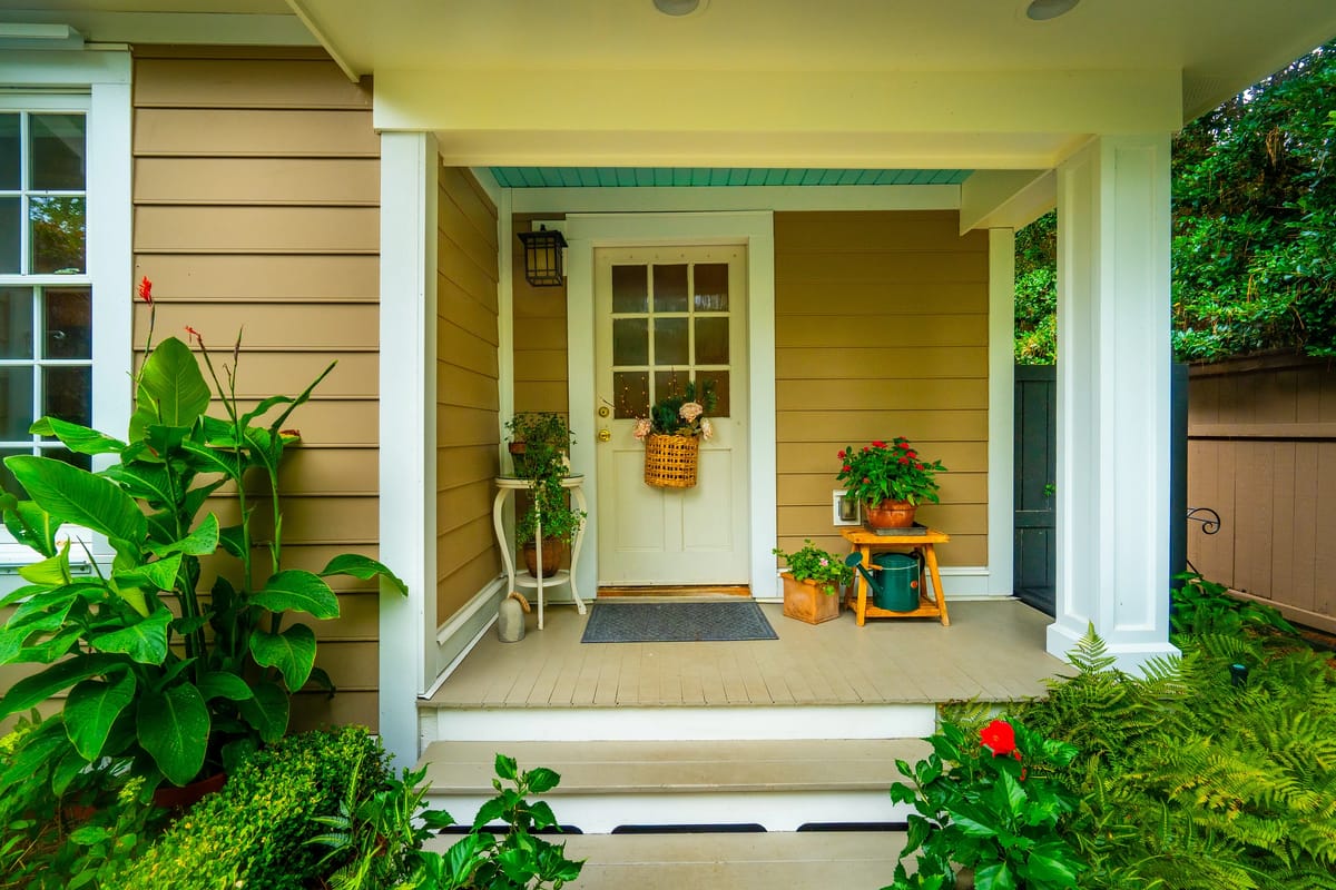 Exterior front entrance with white door, potted plants, and covered porch.
