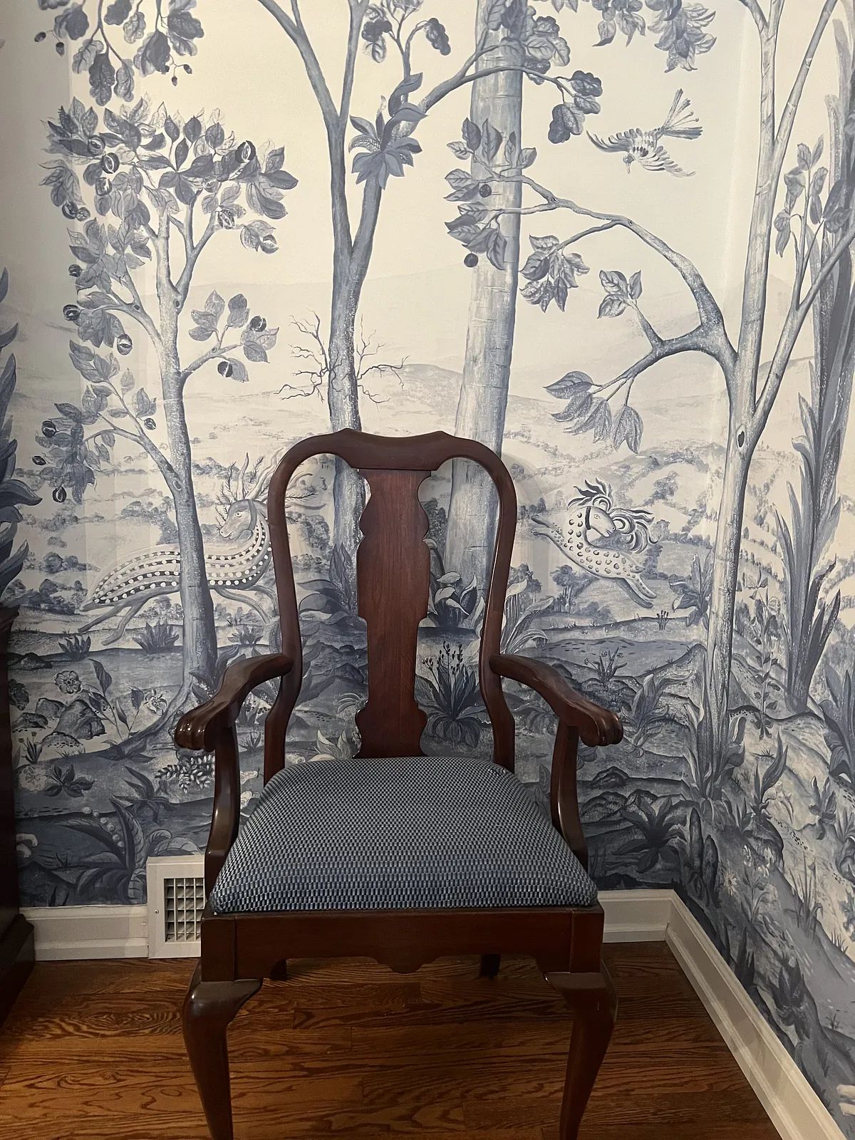 Wooden chair against blue and white wallpaper depicting trees and birds.