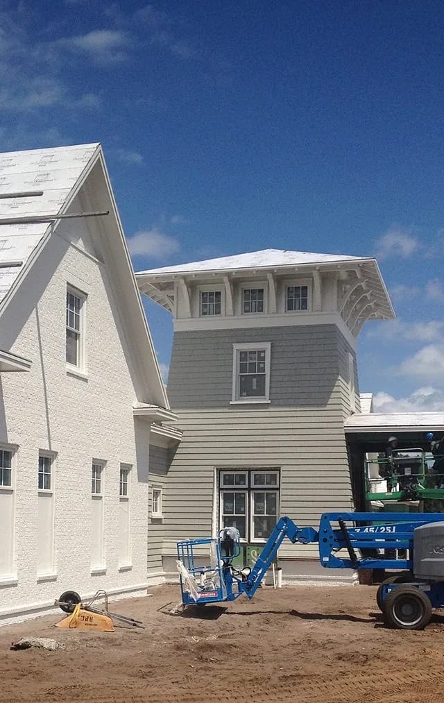 Exterior view of a building with white and gray facades and construction equipment.