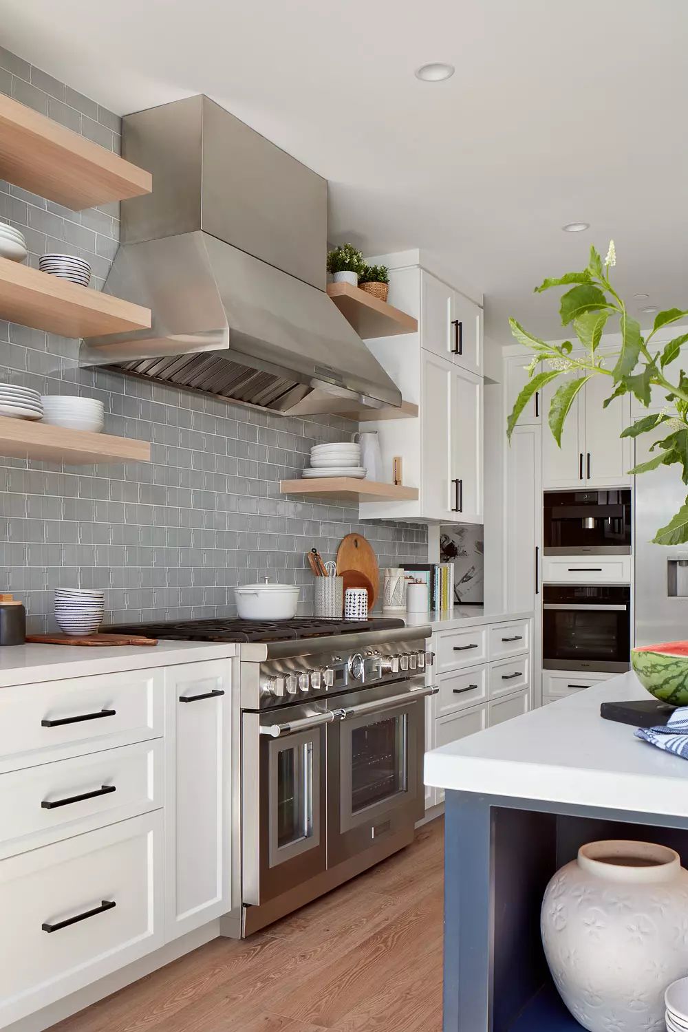 Kitchen with white cabinetry, stainless steel range, open shelving, and central island with seating