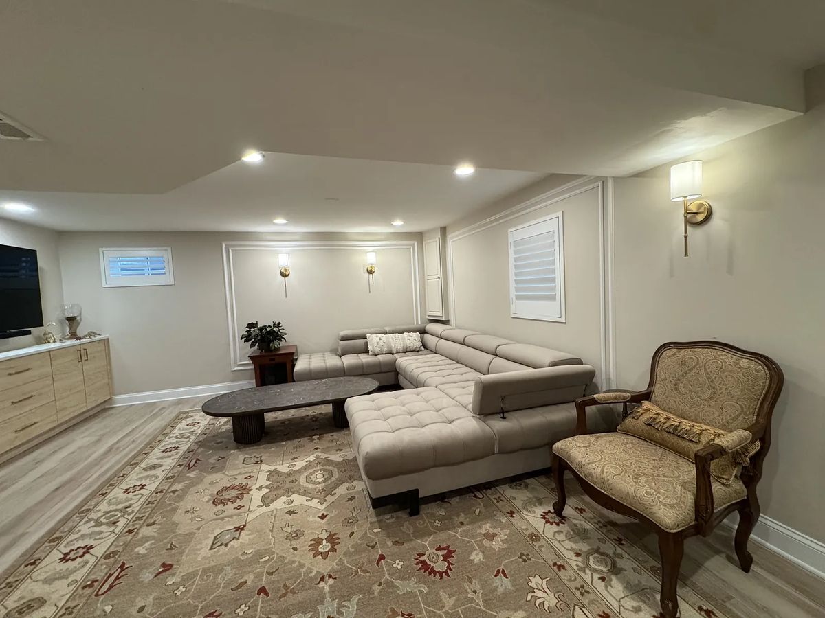 Living room with sectional sofa, coffee table, decorative rug, wall-mounted TV, and wall sconces.