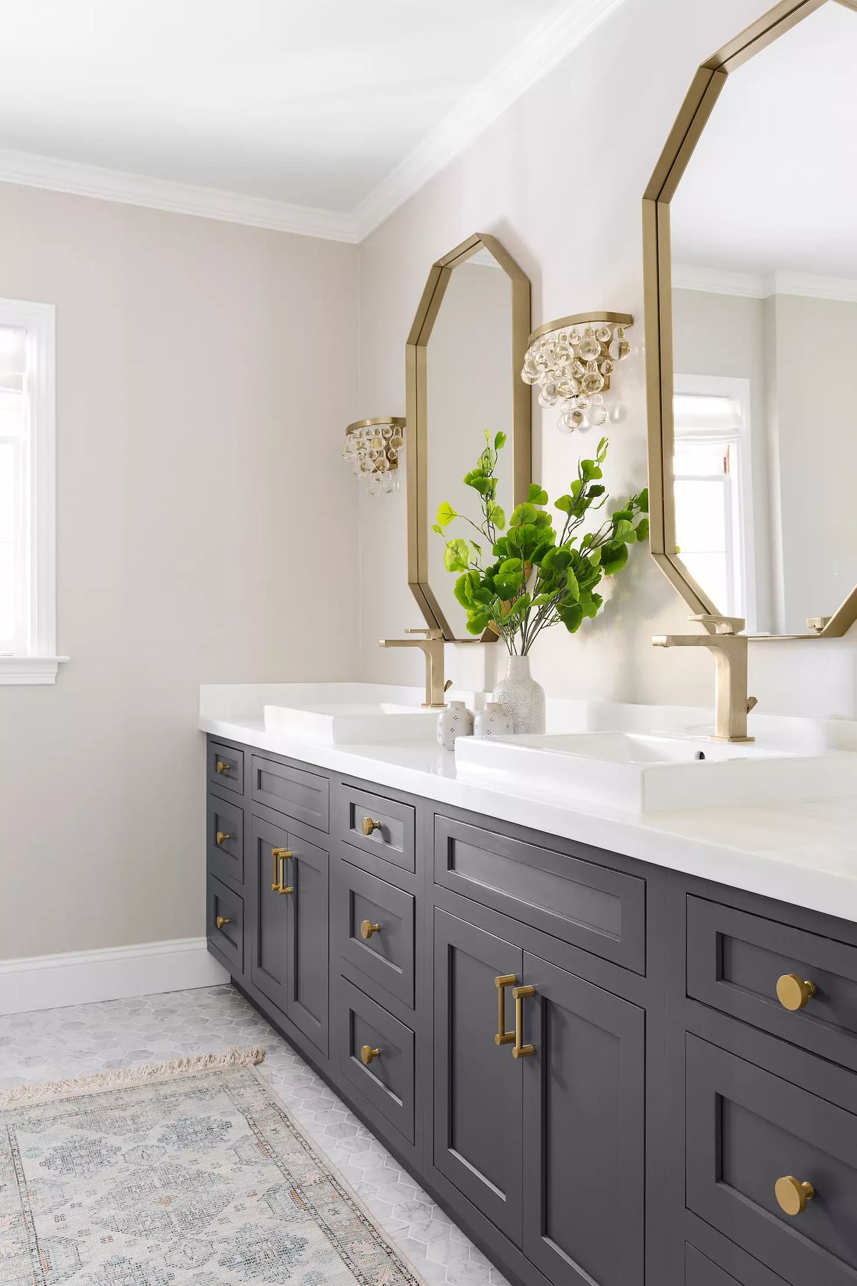 Bathroom with double vanity, dark gray cabinetry, octagonal mirrors, and decorative light fixture.