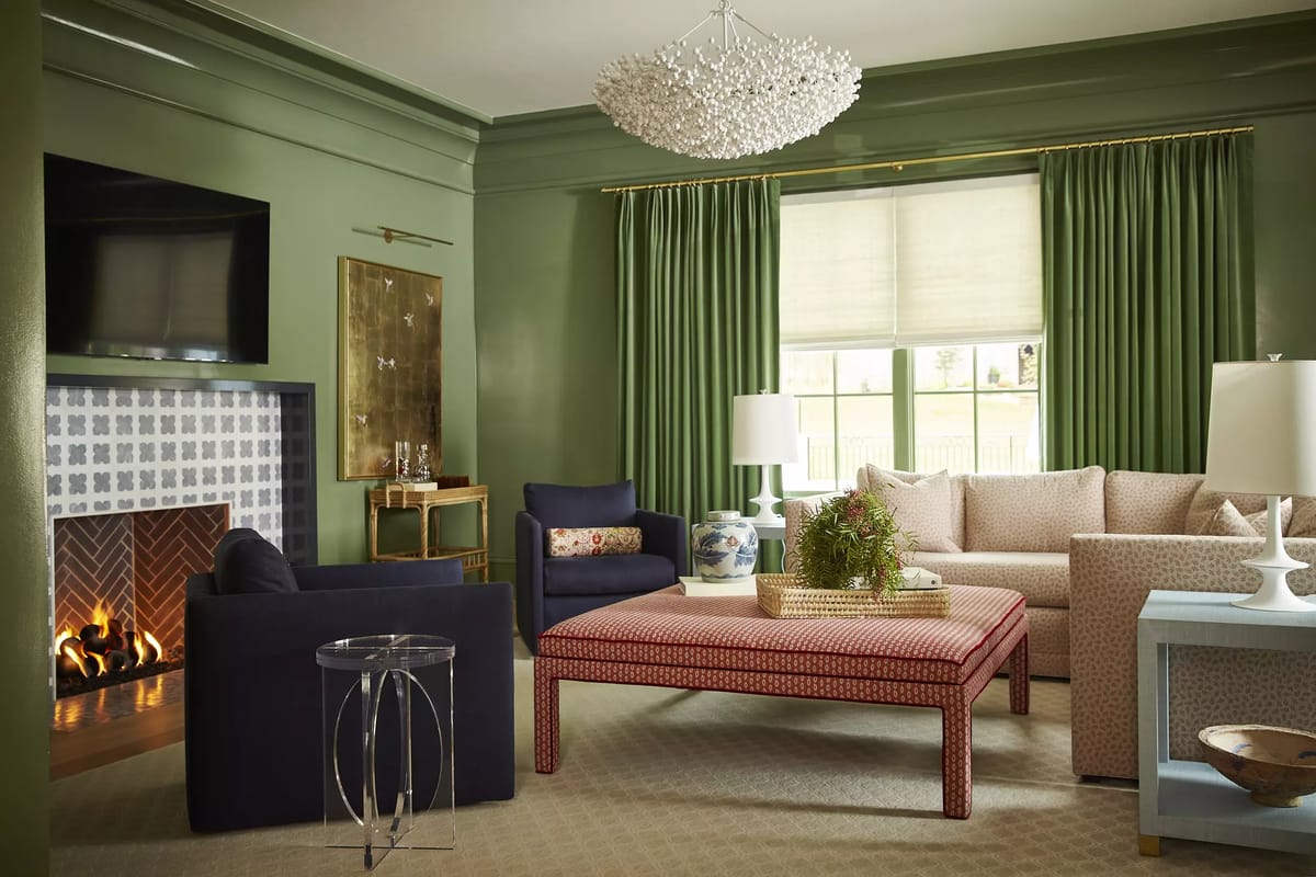 Living room with green walls, patterned coffee table, blue sofa, light sofa, and large window.