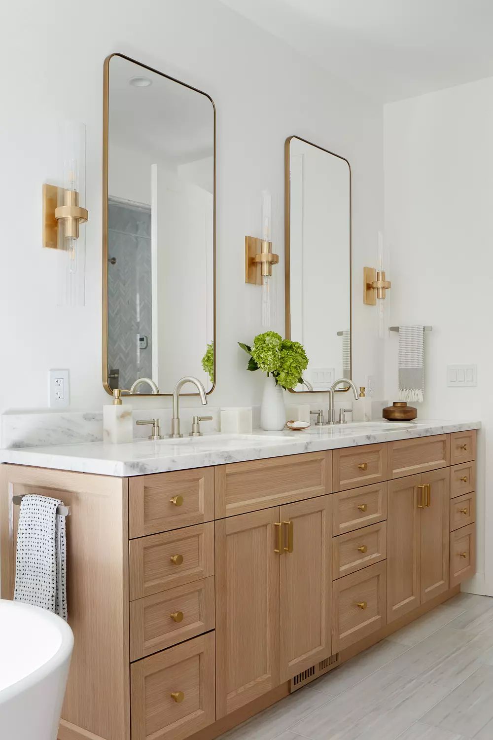 Bathroom with double vanity, marble countertop, freestanding bathtub, and greenery on the vanity