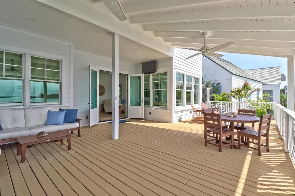 Deck with wooden floor, sectional sofa, coffee table, and dining table with chairs.