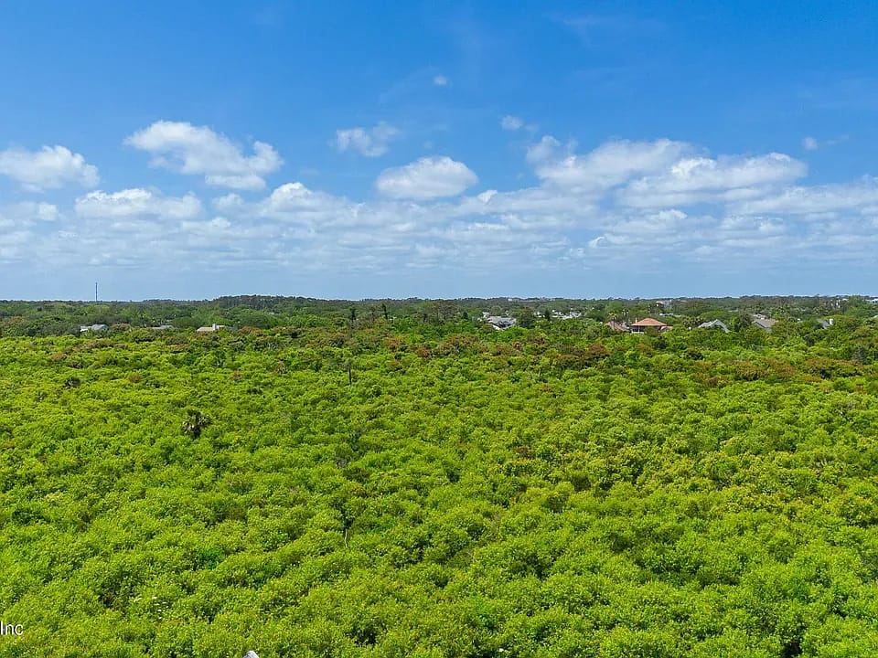 Expansive green landscape with scattered houses and a blue sky.