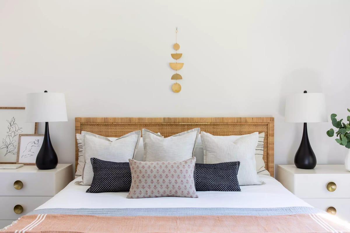 Bedroom with wooden bed, decorative pillows, nightstands, table lamps, artwork, and hanging decoration.