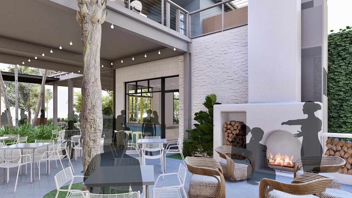 Patio with stone fireplace, wicker chairs, dining tables, greenery, and large windows