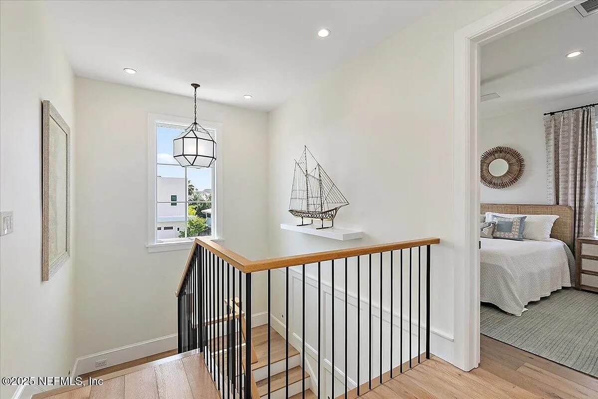 Hallway with wooden staircase, black railing, window, and decorative ship model on a ledge.