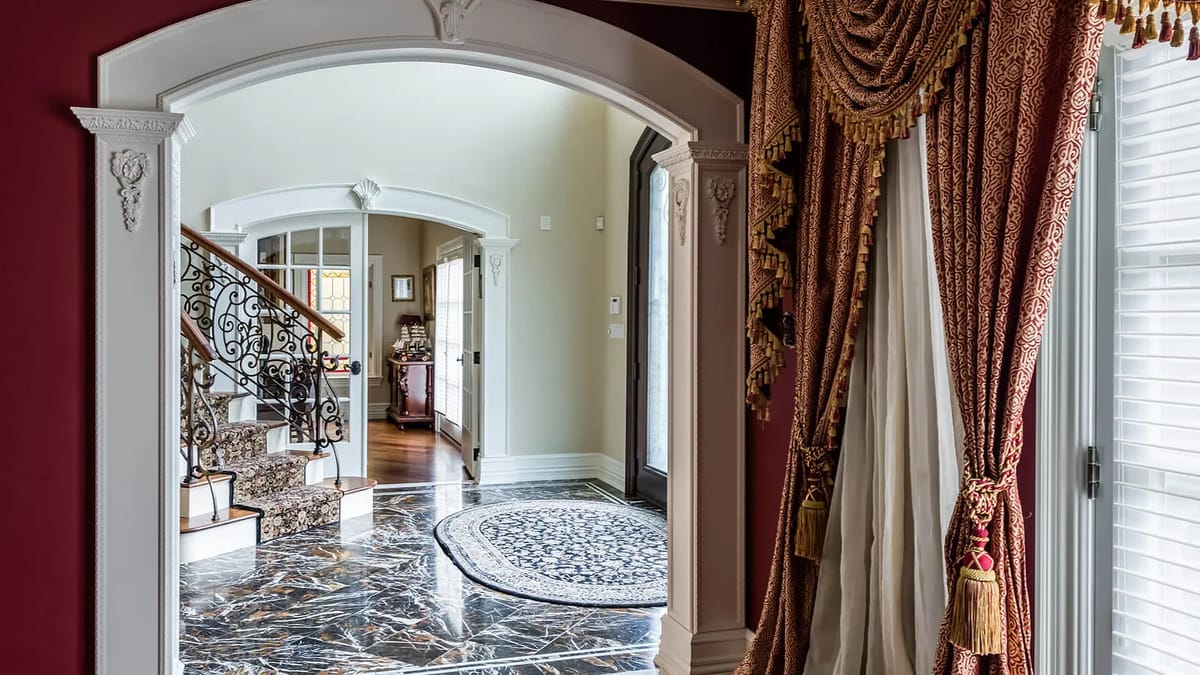 Foyer with marble floor, decorative rug, ornate staircase, and detailed moldings.