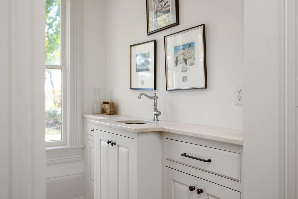 Kitchen with white cabinetry, light countertop, single basin sink, and framed artwork.