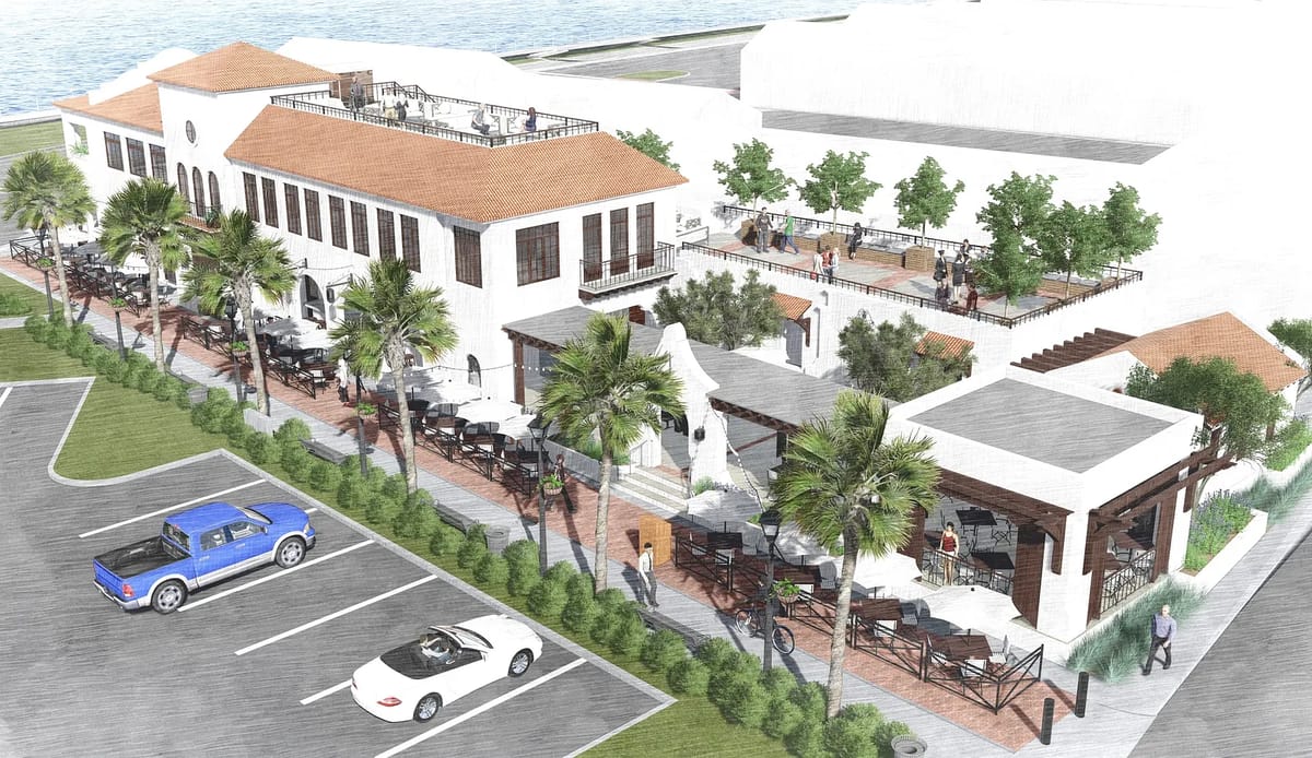 Exterior view of a two-story building with patios, palm trees, and parked vehicles.