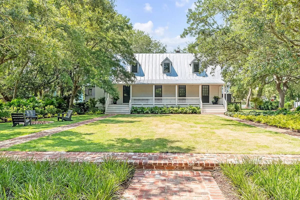 Exterior front with house, metal roof, porch, brick walkway, lawn, and landscaping.