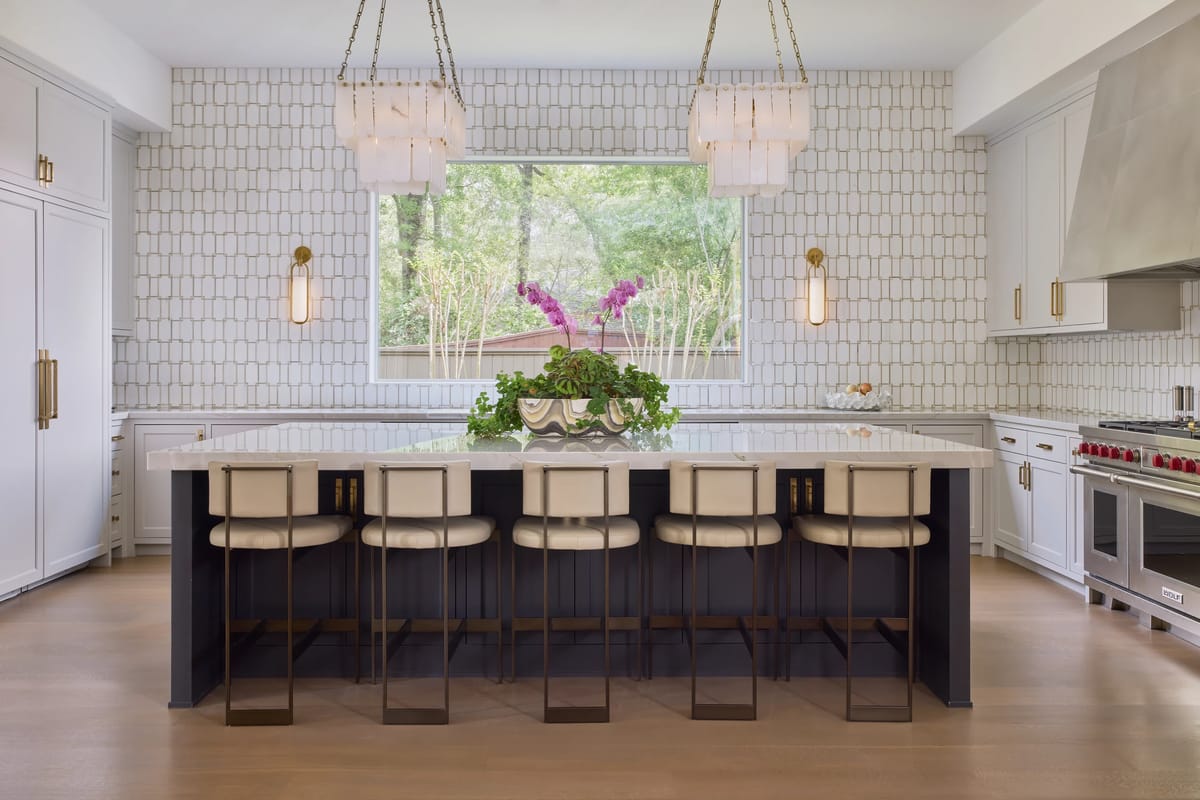 Kitchen with central island, bar stools, stainless steel range, tiled backsplash, and large window.
