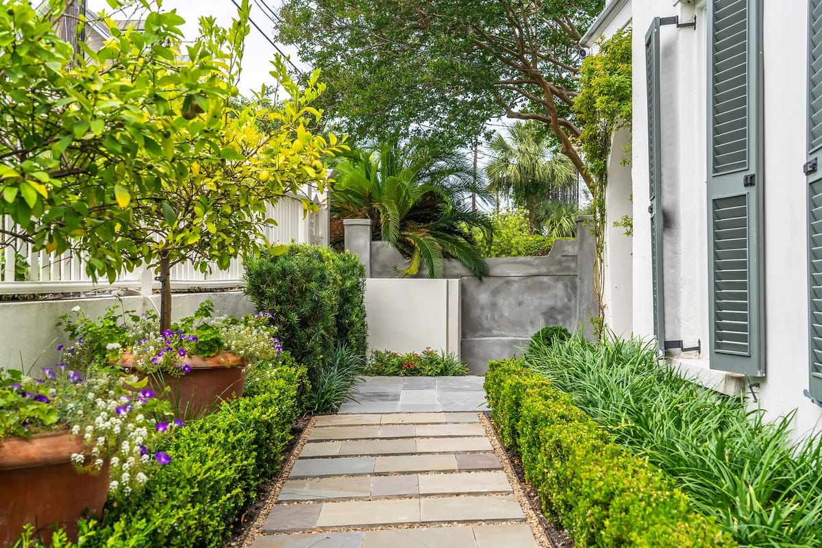 Garden path with stone pavers flanked by greenery and flowering plants.