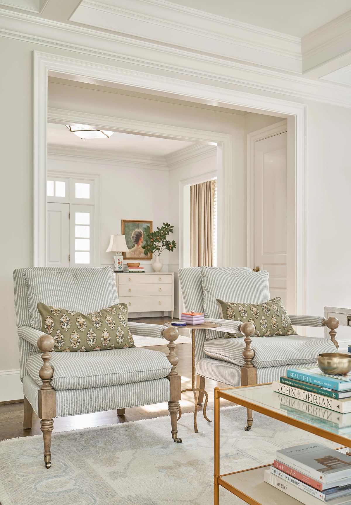 Living room with striped armchairs, coffee table, side table, chest of drawers, and large window with curtains.