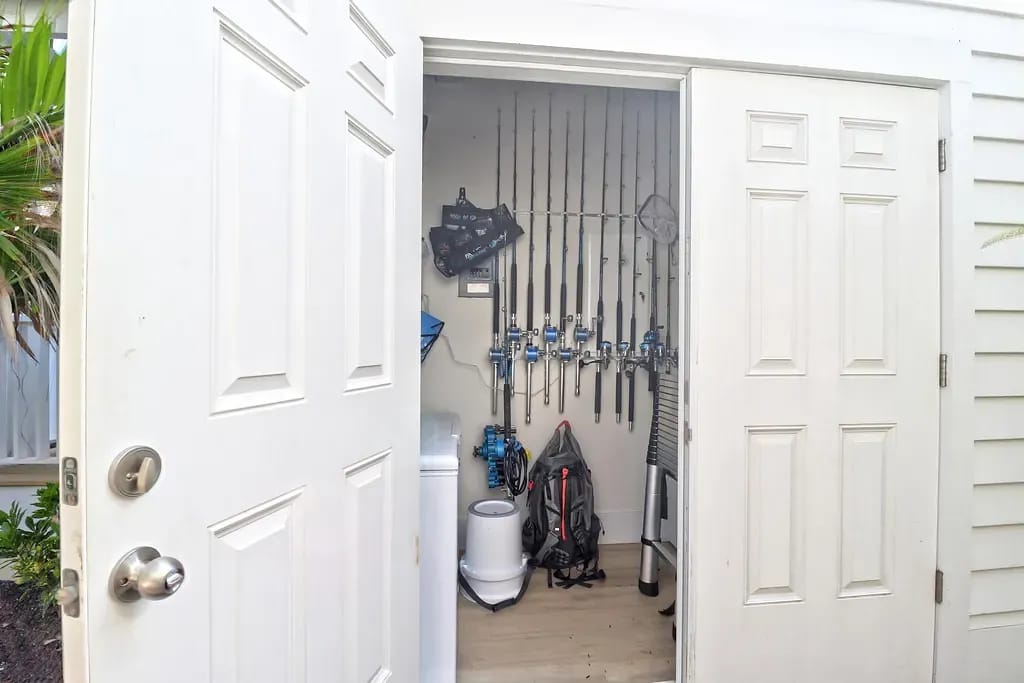 Closet with fishing rods, storage container, backpack, and a toilet in the corner