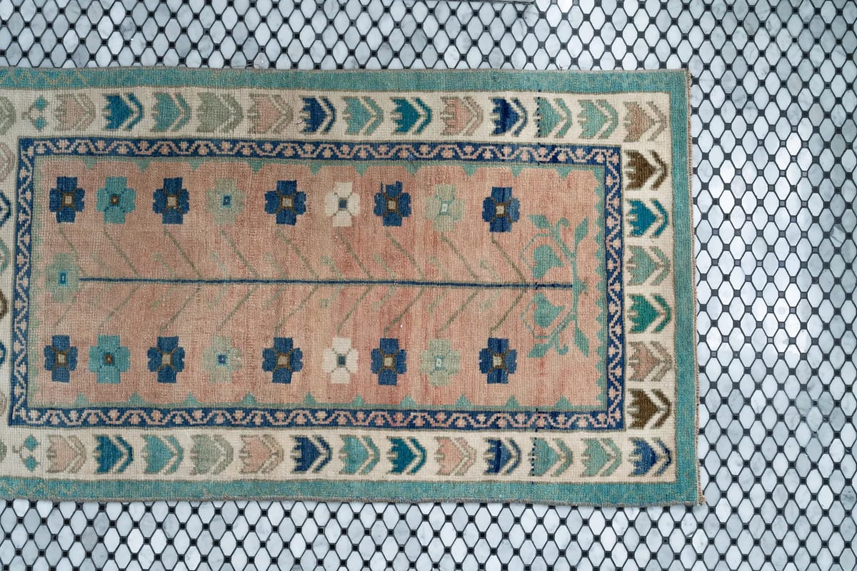 Area rug with floral and geometric pattern on black hexagonal tile floor.