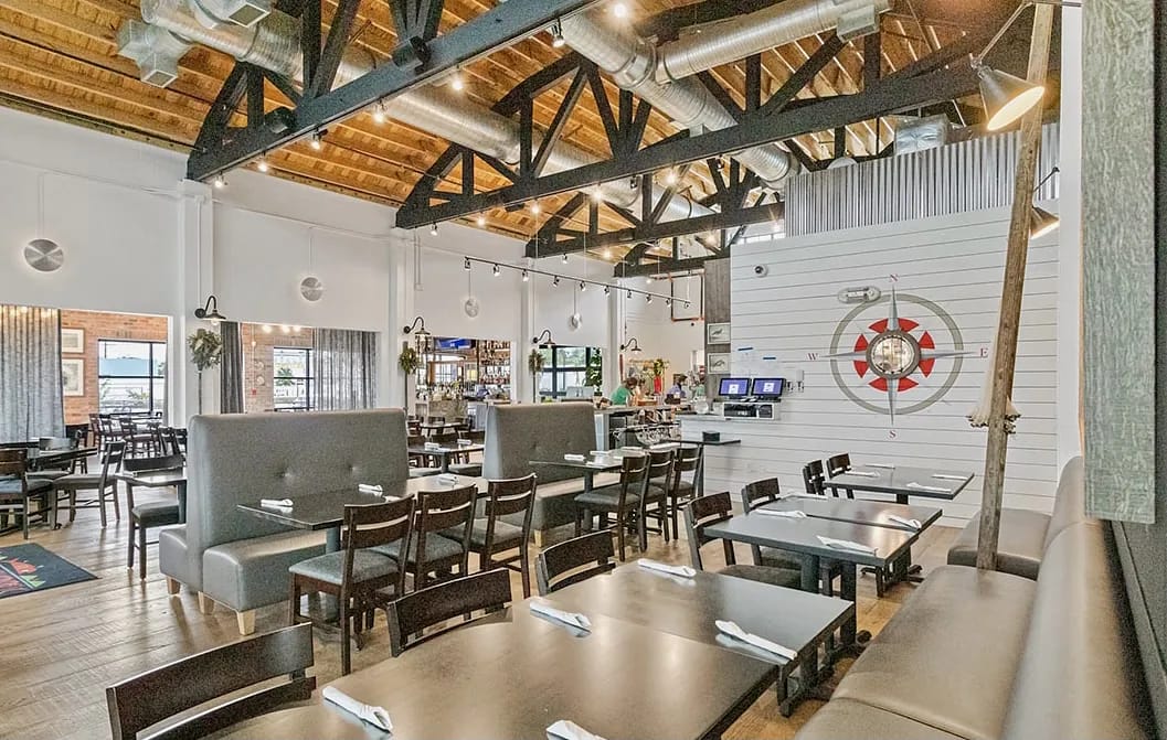 Dining room with dark wood tables, booths, exposed beams, and a decorative wall feature.
