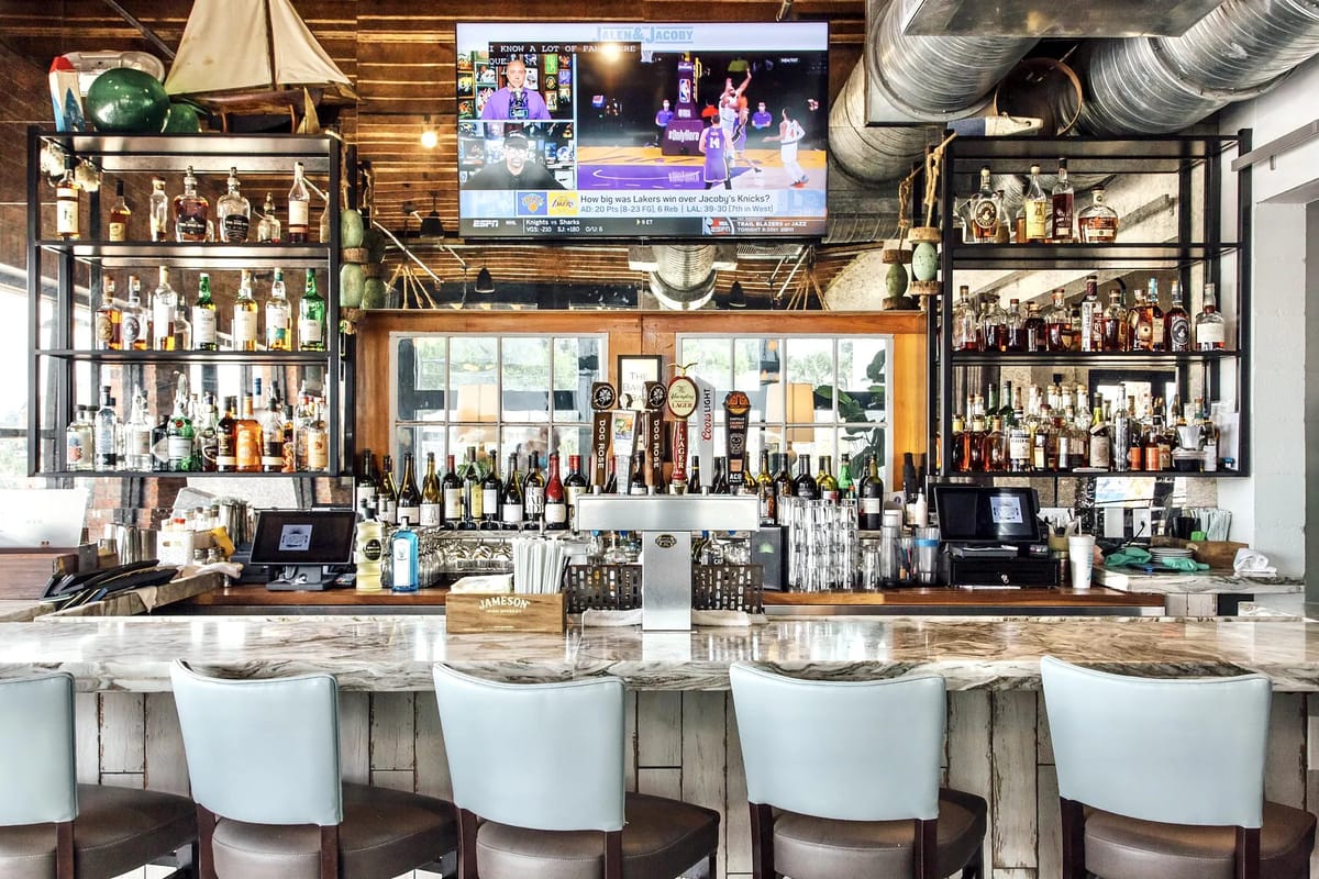Dining room with marble bar counter, high stools, liquor shelves, and mounted television.