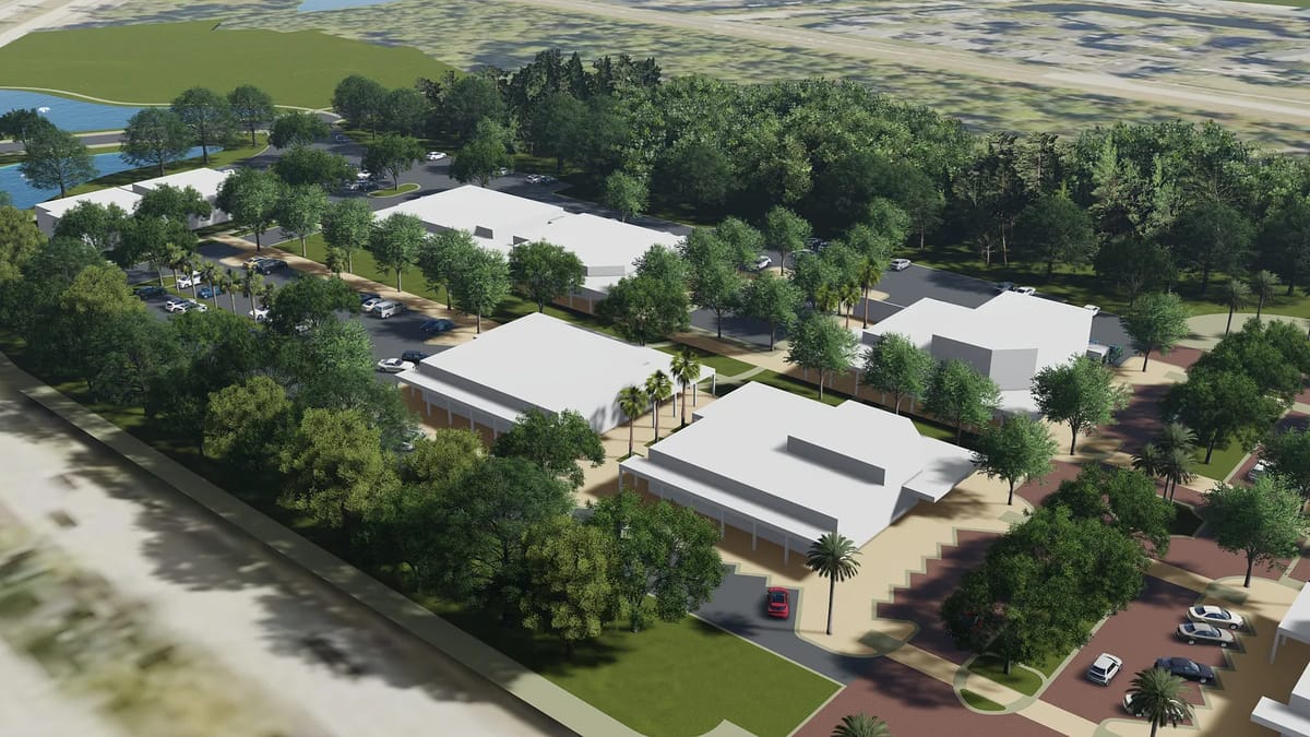 Aerial view of a commercial development with buildings, landscaping, parking, and a water body.