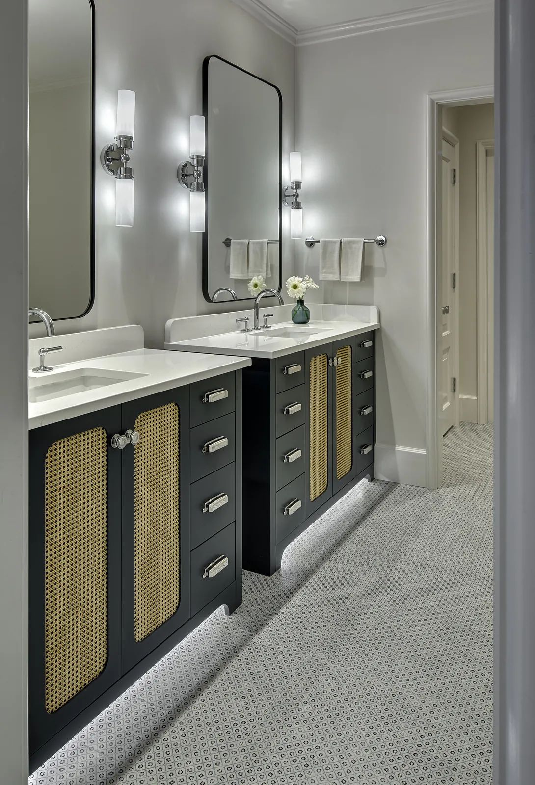 Bathroom with double vanity, black cabinets, dual sinks, large mirrors, and patterned tile flooring.