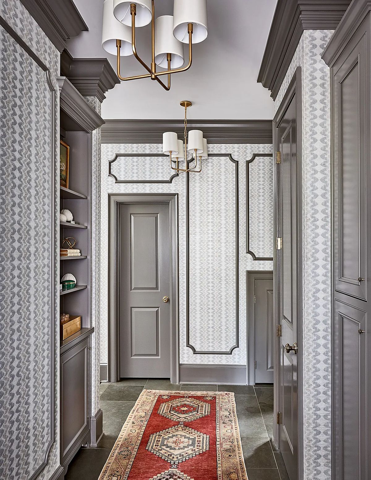 Hallway with patterned wallpaper, runner rug, built-in cabinetry, and molding details.