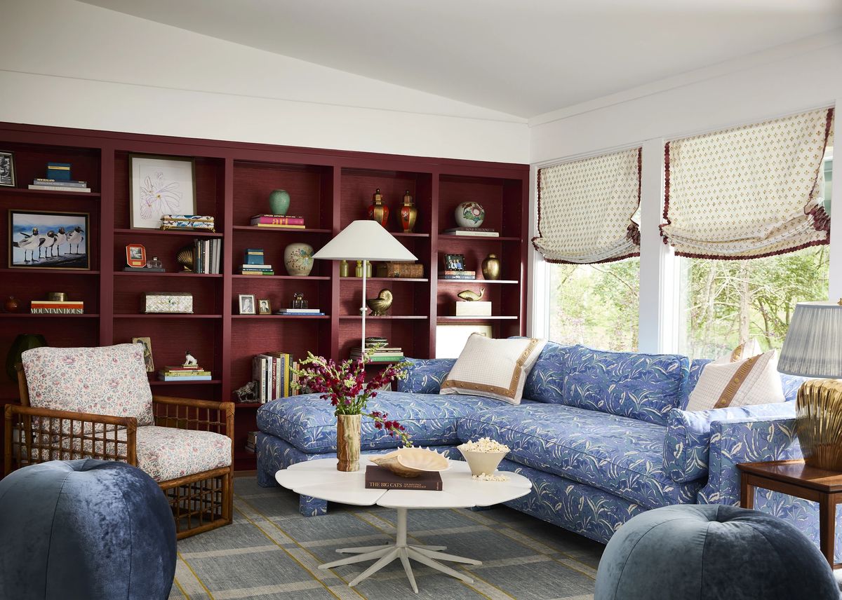 Living room with blue floral sofa, round coffee table, armchair, built-in shelves, and gray area rug.