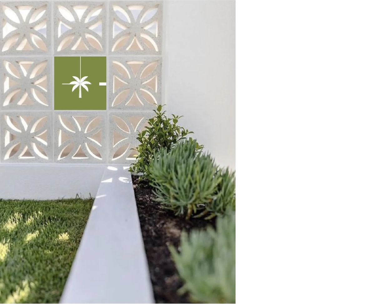 Garden area with succulent plants, decorative wall cutouts, and grass in the foreground.