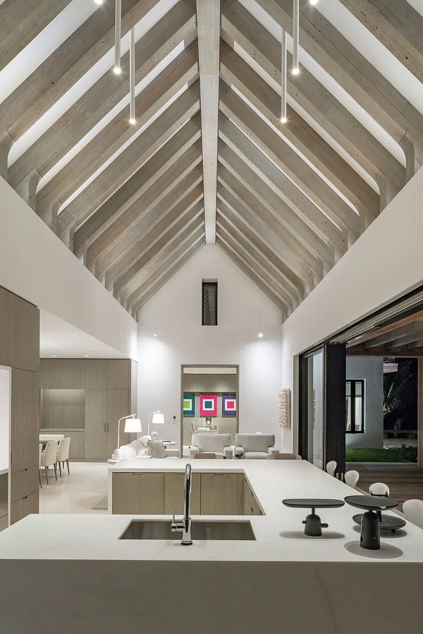 Kitchen with central island, concrete counters, wood cabinetry, exposed beams, and large windows