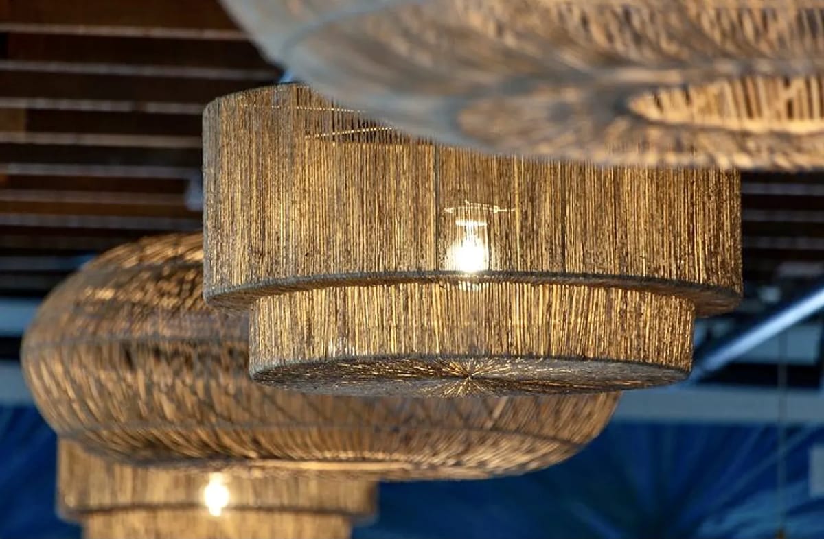 Woven pendant lights with natural color hanging from a wooden ceiling, showcasing a layered texture.