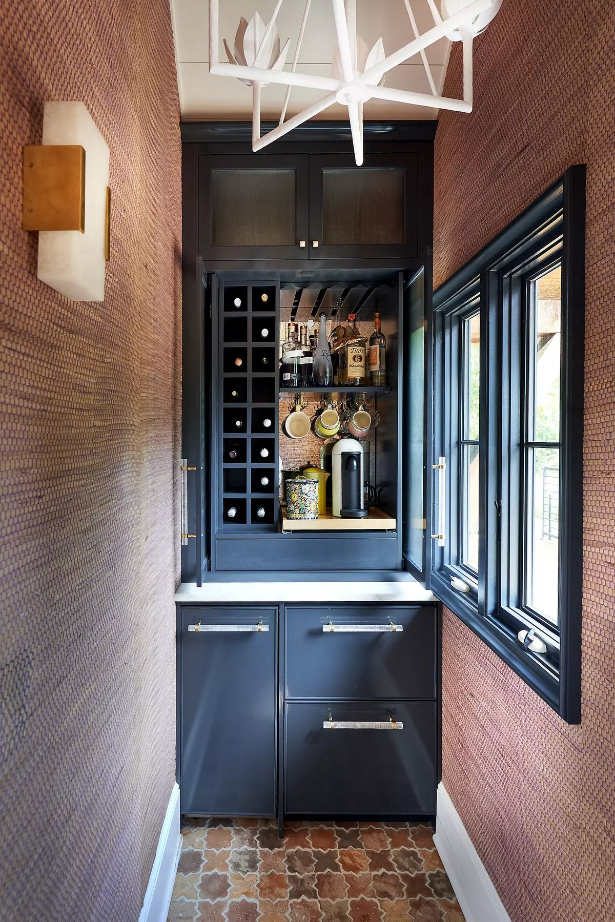 Butler's pantry with dark cabinetry, countertop, wine storage, coffee maker, and textured wallpaper.