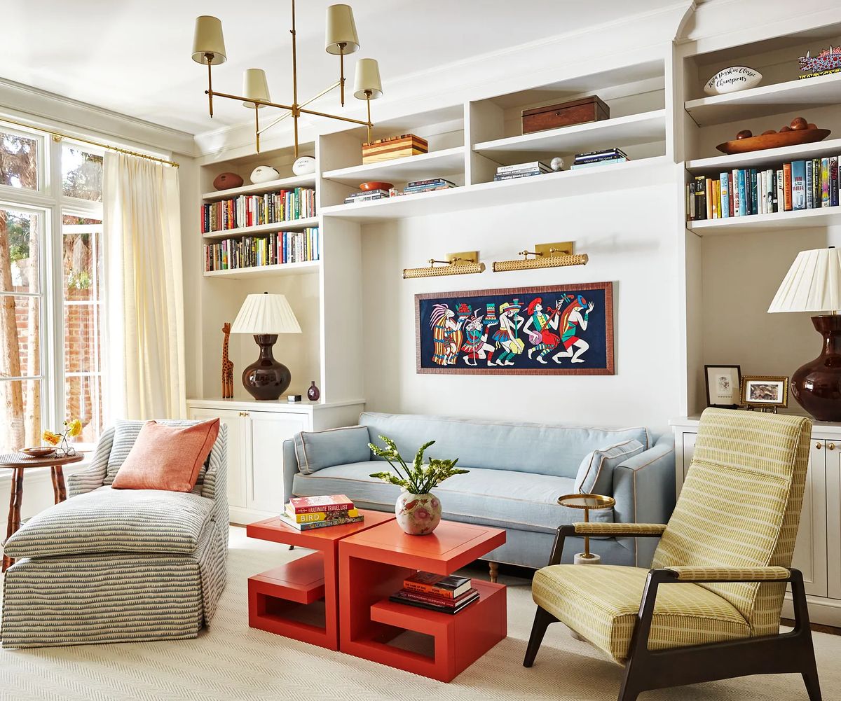 Living room with light blue sofa, orange coffee table, striped chair, green armchair, and built-in bookshelves.