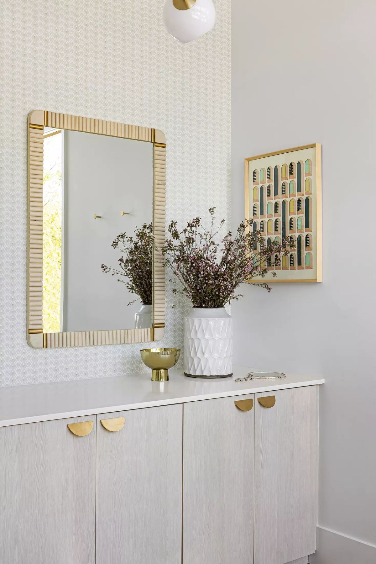 Foyer with wall-mounted mirror, console table, vase with flowers, and patterned walls.