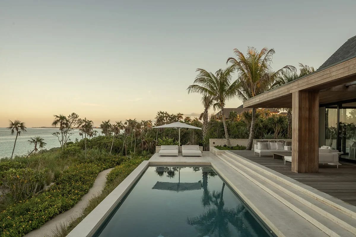Outdoor space with swimming pool, palm trees, lounge chairs, and covered dining area with ocean view.