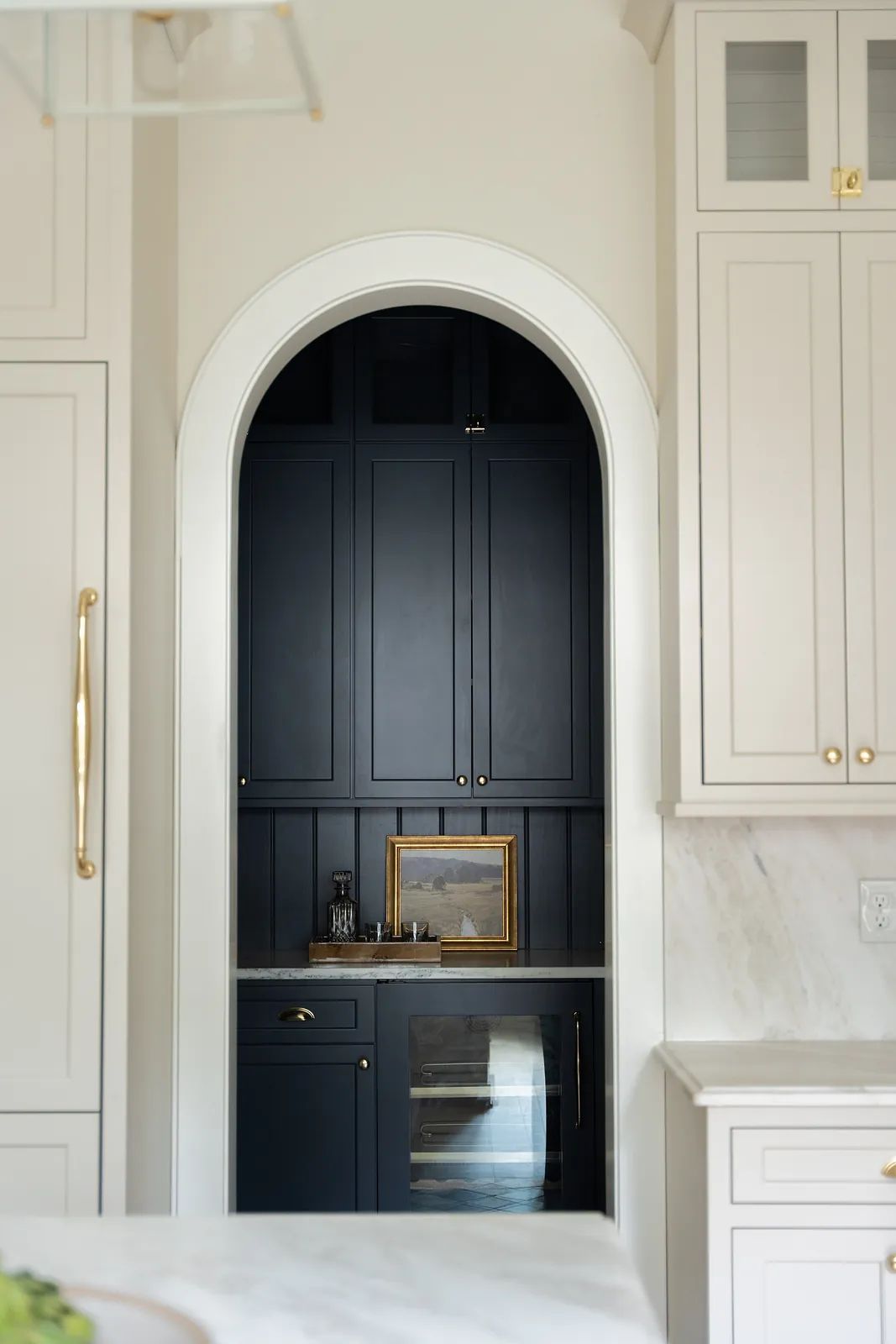 Kitchen with navy cabinets, marble countertop, arched opening, glass doors, and a built-in wine cooler.