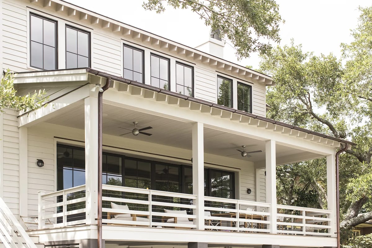 Exterior rear with covered porch, white railings, sliding glass doors, and ceiling fans.