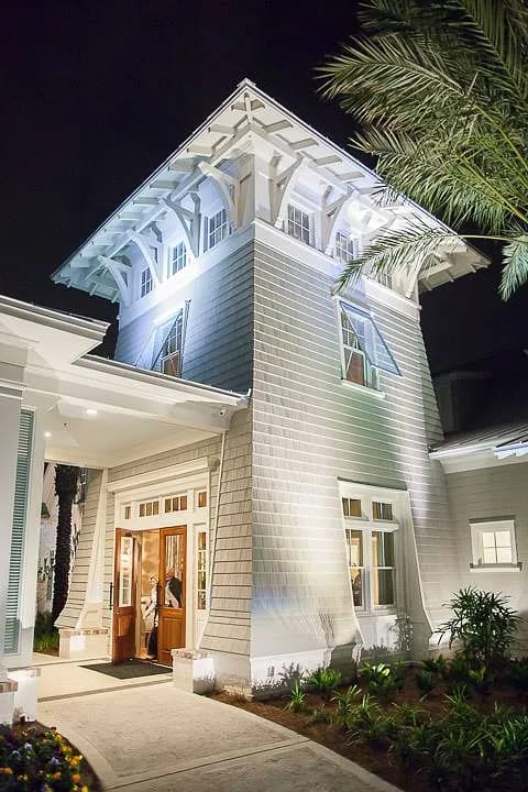 Exterior front view of a house with a tall tower, large windows, double-door entrance, and landscaped pathway.
