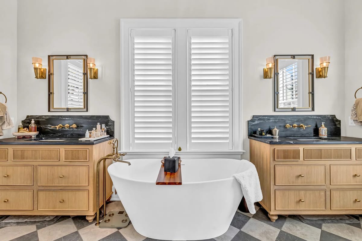 Bathroom with freestanding bathtub, wooden vanities, black countertops, and chevron patterned floor.