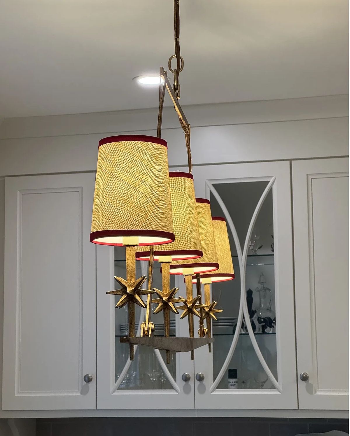 Kitchen with pendant light, white cabinets, gray countertop, and decorative glass door fronts.