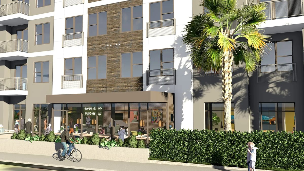 Front view of a multi-story building with large windows, balconies, storefront, and greenery.