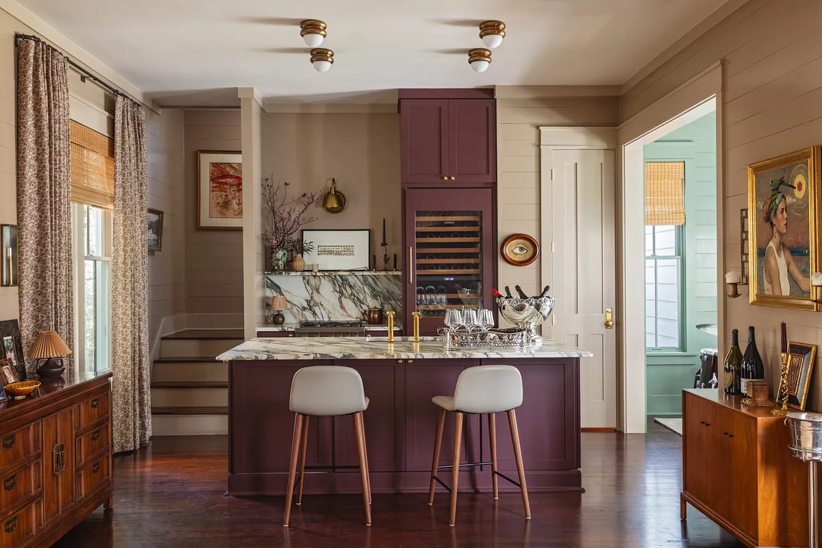 Kitchen with marble countertop, bar stools, cabinets, art, staircase, and wine cooler